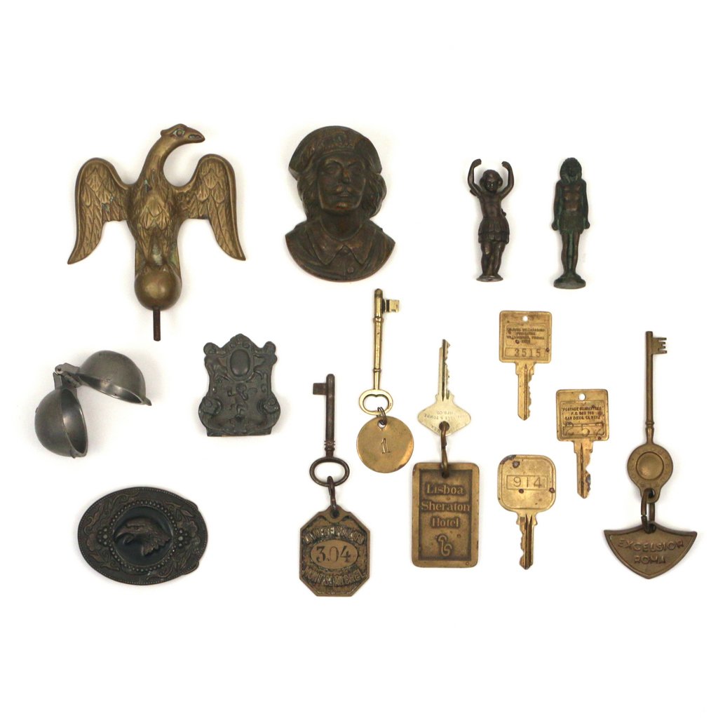 MISC LOT OF BRASS AND MIXED METAL FIGURES AND KEYS: Including a brass eagle finial, a metal paperweight of a mustachioed man, a chocolate mold, a male Egyptian figure, a standing cherubic figure, a belt buckle, a desk ornament, and a variety of hold ho