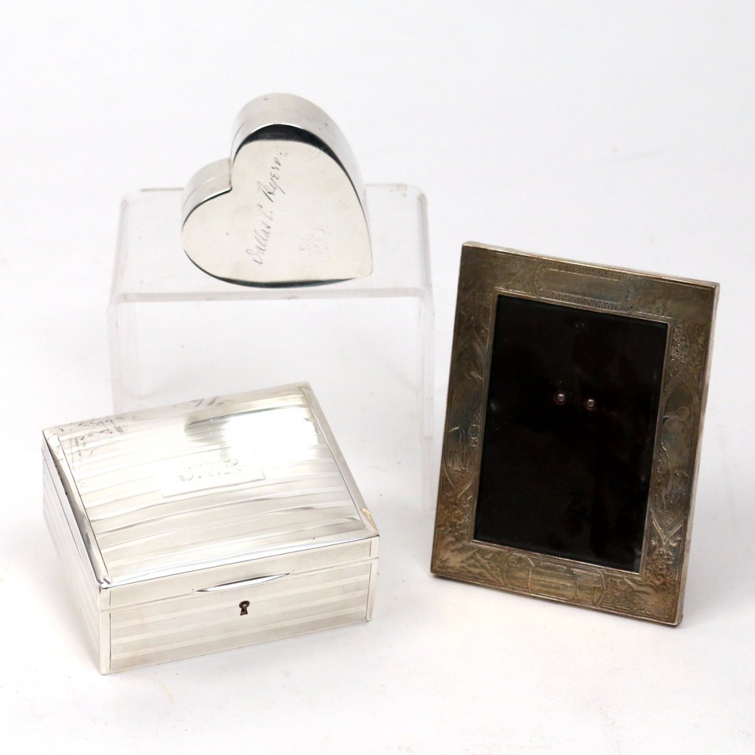 (3pc) STERLING SILVER BOXES AND PICTURE FRAME: Including a Tiffany & Co. sterling silver desktop cigarette box monogrammed J.V.R; a heart-shaped box engraved "Dallas C. Byers" from Deans Fifth Avenue; and a sterling silver Grogan Company baby port