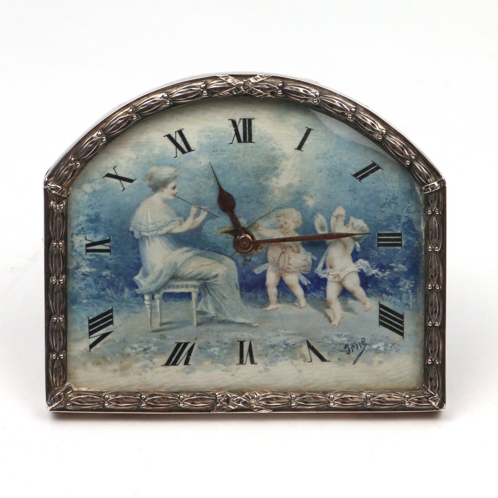 FRENCH STERLING SILVER TRAVEL CLOCK: FRENCH STERLING SILVER TRAVEL CLOCKlate 19th/early 20th Century, of an arched rectangular shape, the face with a painted minstrel scene of a woman and two putti, signed indistinctly 'Jrue' (?), 3-1/4 