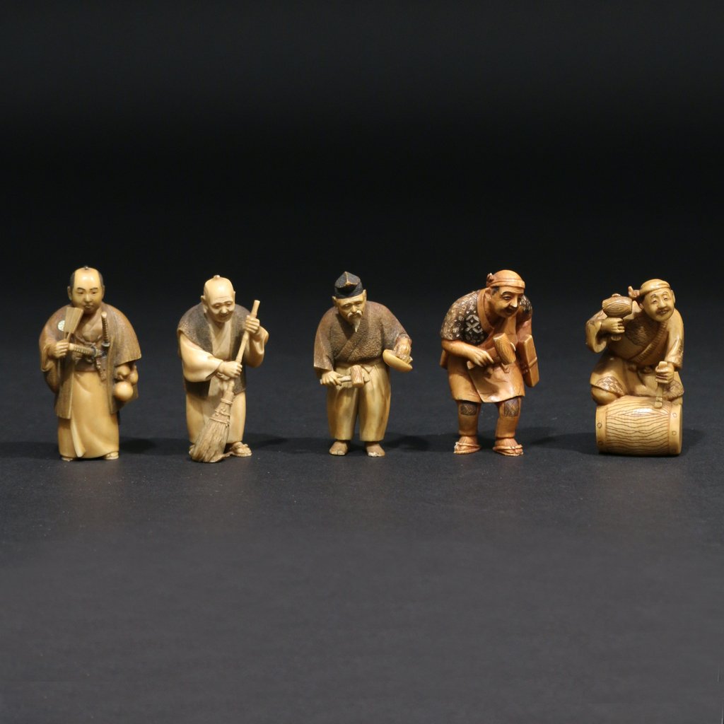 (5pc) JAPANESE CARVED OKIMONOS: Including a man with a mallet kneeling on a barrel; an elderly man holding a broom; a carpenter holding a mallet and a plane (chipped foot); a samurai holding a fan and gourd (missing signature plaque