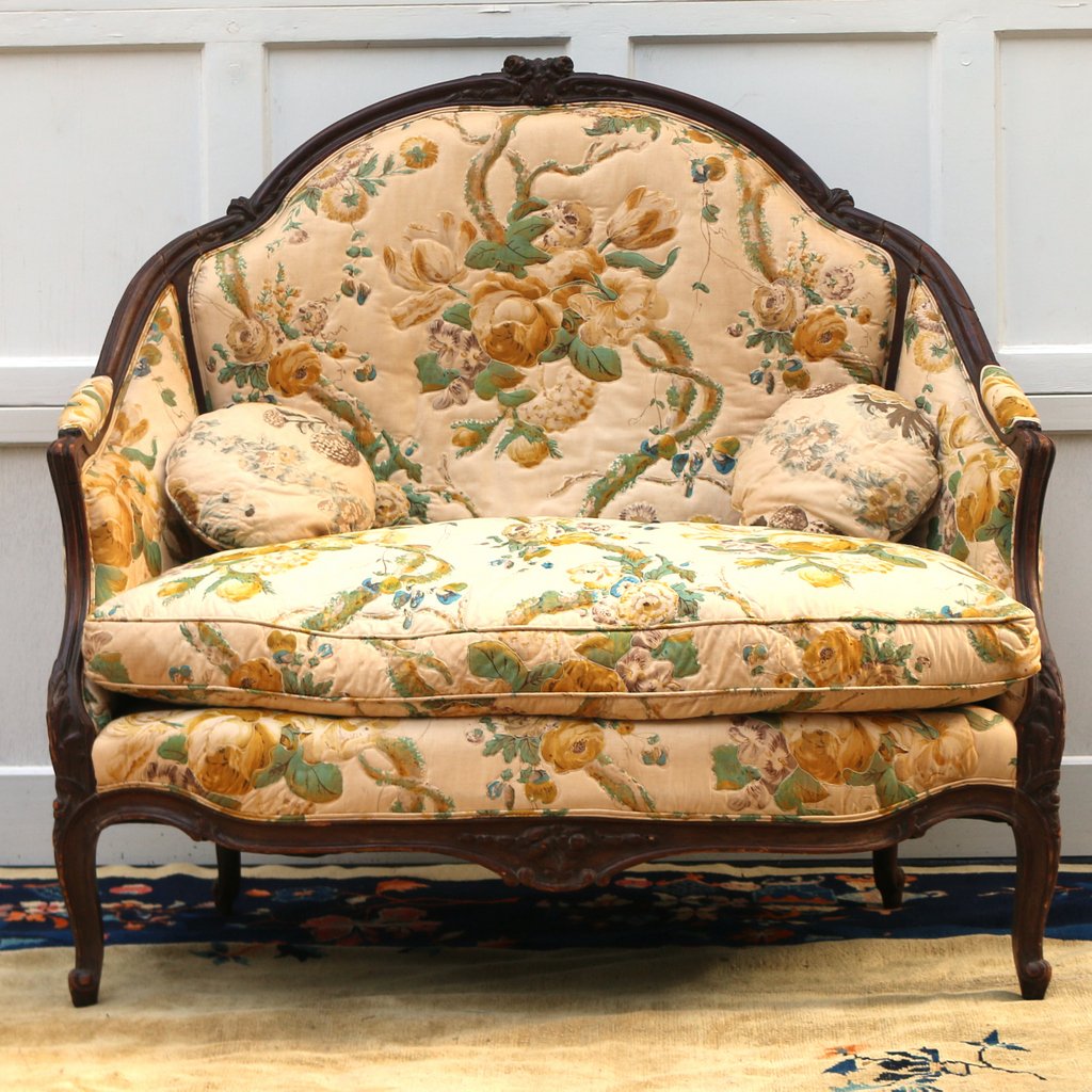 FRENCH CARVED WALNUT BERGERE SETTEE: 19th Century, of large love-seat proportions, with beige floral upholstery, h. 41-1/2 w. 45 d. 29 in.