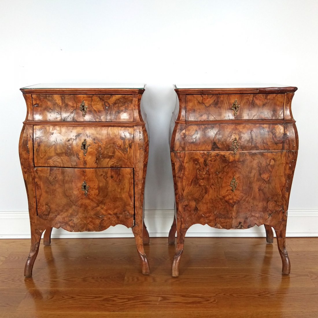 PAIR BURL VENEER BOMBE PETITE COMMODES: Continental, 19th C. or earlier, gallery top with inset glass tops, one commode with three drawers, the other with single top drawer and two false lower drawers; h.30 x w.19 x d.15in.