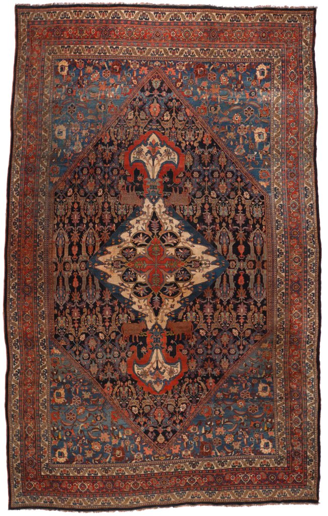 ANTIQUE BIDJAR CARPET: early 20th Century, having an ivory-colored medallion with spade-form drops on either side flanked by cows and a farci inscription, all on an indigo field with a stylized lattice design enclosed by me
