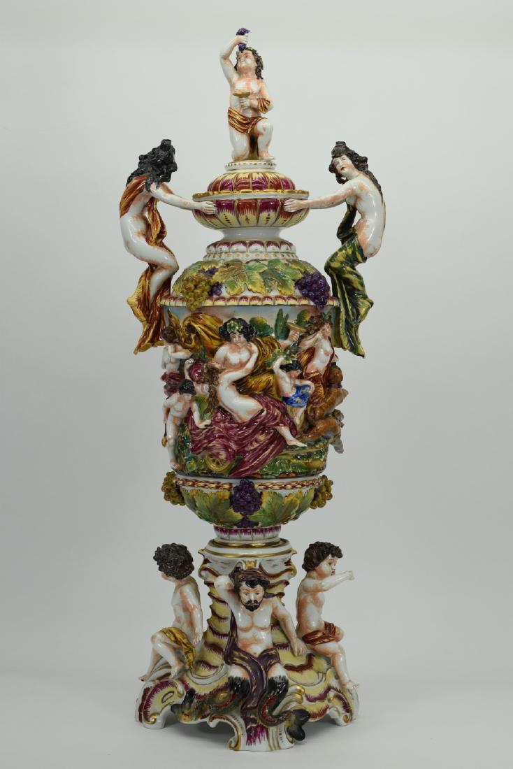 CAPODIMONTE PORCELAIN CENTERPIECE LIDDED URN VASE: Large Italian porcelain scenic covered vase; cherubs, putto, maidens, other mythical figures, scenes of bacchanalia, and more. Three pieces: base and body (connected with a through-bolt) and lid. Ille