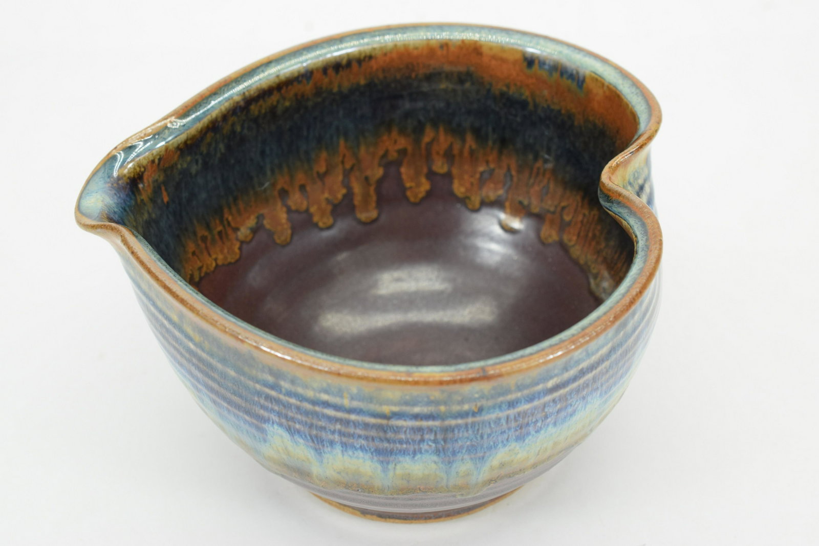 SIGNED IRIDESCENT ART POTTERY HEART BOWL: Multi-color (blue, purple, green, yellow, brown, maroon) drip glaze pottery heart shaped bowl signed illegibly as well with an unknown symbol. Measures approximately 4-1/2" H x 7-1/2" W x 7-1/2" D. We