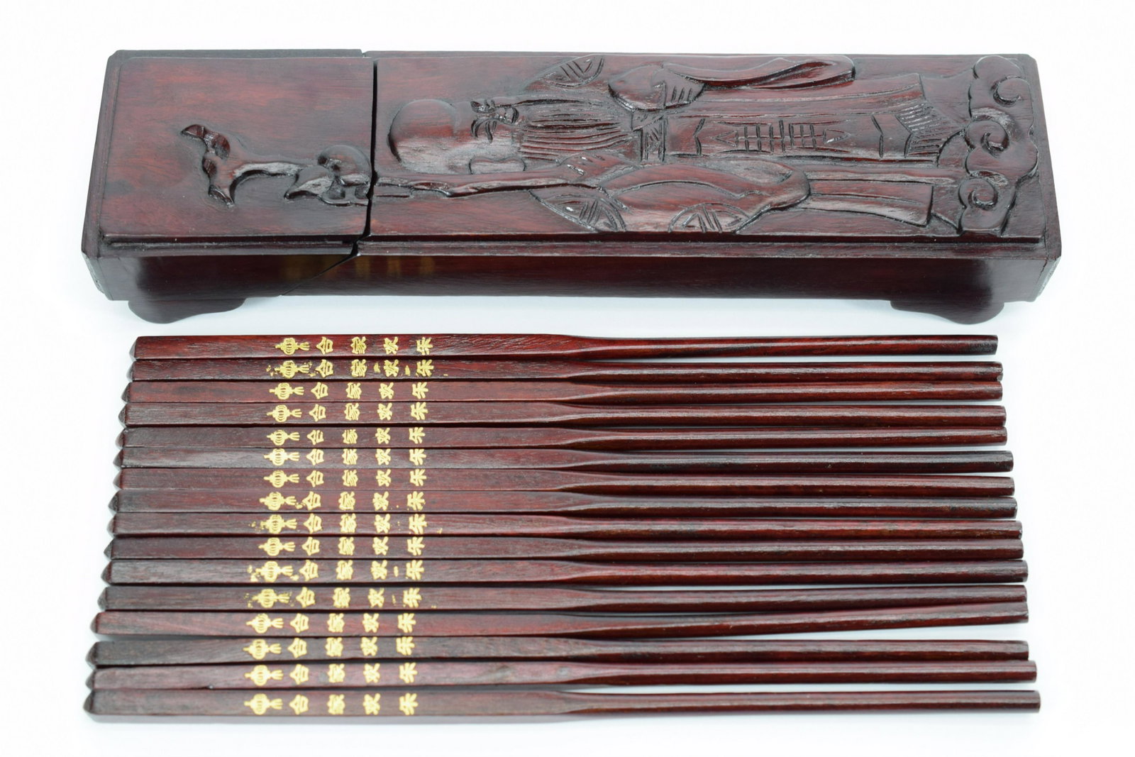CHINESE CARVED ROSEWOOD CHOPSTICKS HINGED BOX: Chinese wood box having carved "God of Longevity" to the front and holding eight (8) sets of rosewood chopsticks each impressed with gold tone calligraphy to the handles. Box measures 10-1/4" L x 2-3/