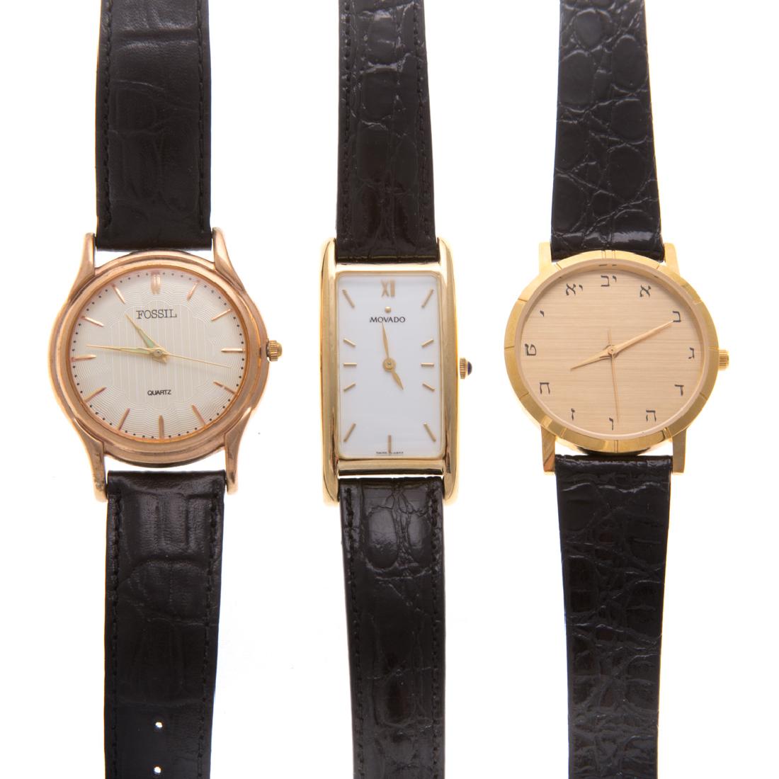 A Trio of Gent's Wrist Watches: 1) Movado tank style watch, gold plate with stainless back, quartz movement, black strap, 2) Fossil watch with round cream colored face, quartz movement, black strap and 3) Gold plate round dial with
