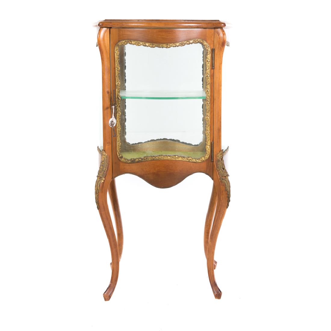 Louis XV style fruitwood brass mounted vitrine: 20th century; beveled glass top, compartment with shelf enclosed by bowed glass door and sides, cabriole legs, brass sabots, 38 in. H., 20 1/2 in. W., 20 1/2 in. D.