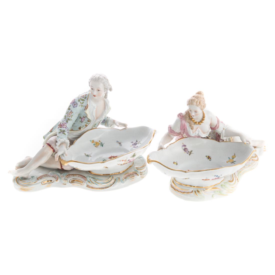 Pair of Voigt porcelain figural sweet meat stands: early 20th century; each modeled as recumbent rococo man and woman, next to oblong floral decorated bowl, 7 in. H., 12 in. W.