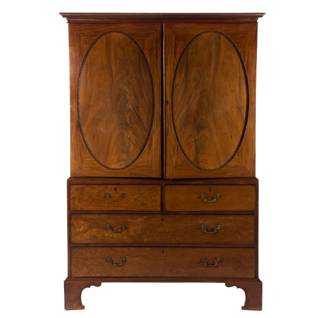 George III style mahogany linen press: early 19th century; upper with flat molded top, dentil molded edge, compartment with pullout shelving enclosed by central oval paneled doors, lower with two medium drawers over two long drawers, brack