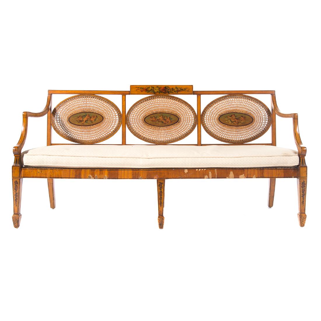 Edwardian satin wood & painted triple-back settee: paper label "Pope and Sons, Hammersmith", early 20th century; flat crest rail with central painted tablet, three oval backrests with cane and central painted plaques, down swept arms, cane seat with c