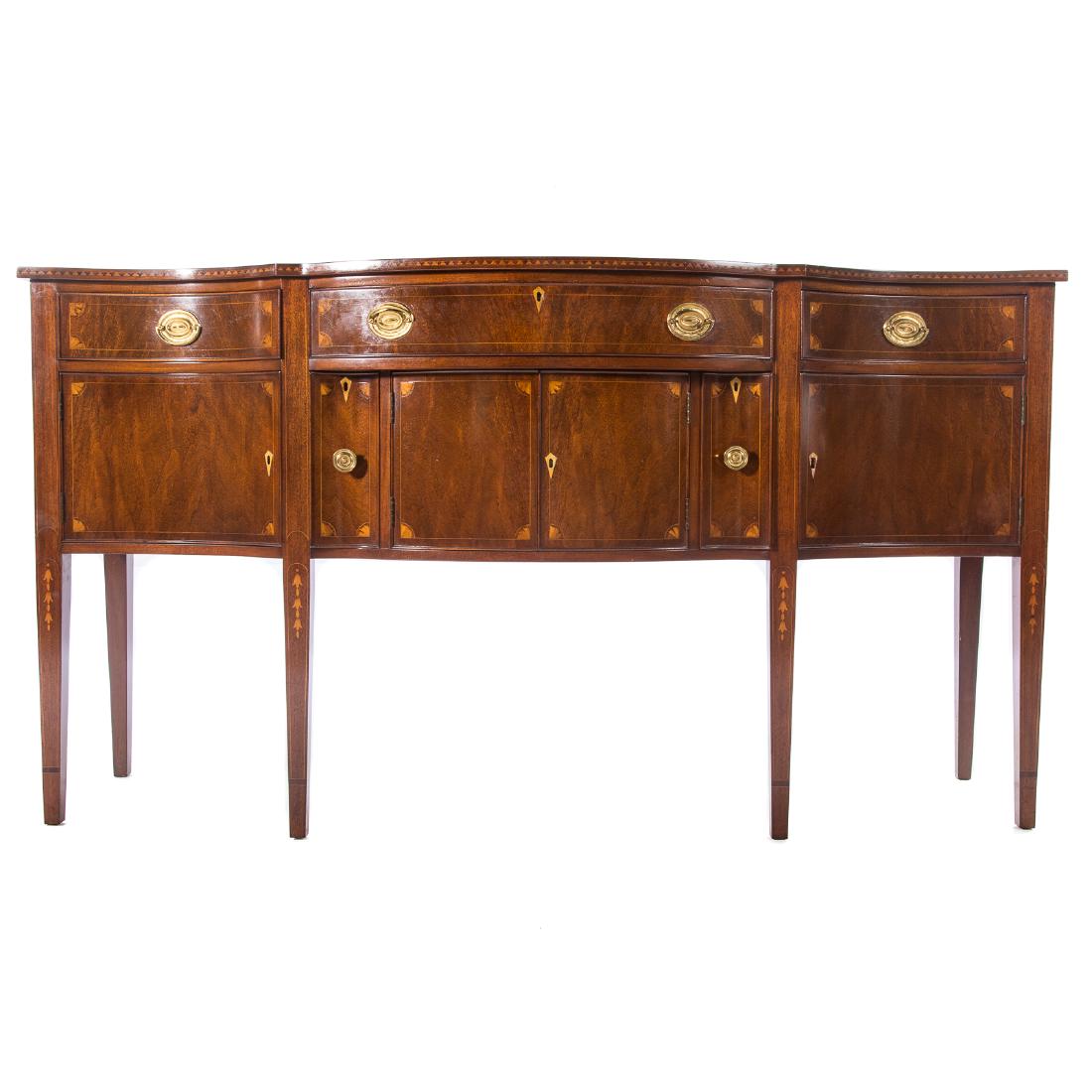 Federal style inlaid mahogany sideboard: 20th century; serpentine top with geometric inlay edge, bow-front long drawer, over compartment enclosed by rounded paneled doors, and bottle drawers, flanked by inverted short drawers and paneled doo