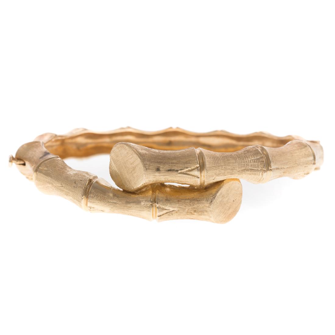 A Ladies Bamboo Bangle Bracelet in 14K: 14K yellow gold bracelet with bamboo bypass design, brushed finish, oval hinged bangle bracelet, and hidden clasp with figure 8 safety, 2.25 in. L, 22.4 grams