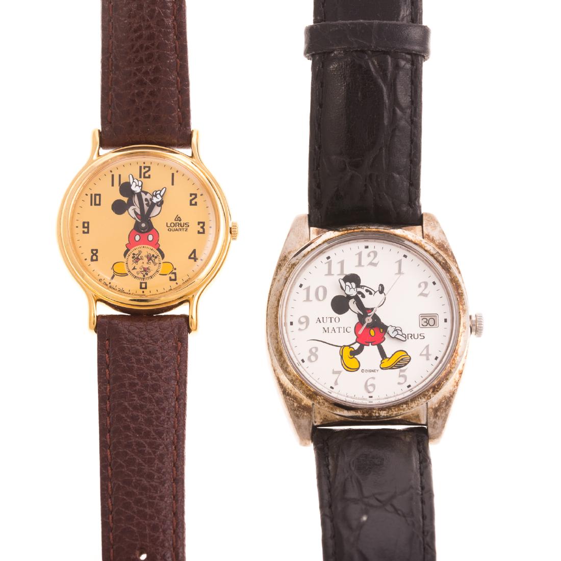 A Pair of Mickey Mouse Watches by Lorus: 1) stainless steel Mickey Mouse watch by Lorus, 37.5mm, automatic movements, date window, serial #Y621-6050 with brown strap and 2) stainless steel and gold toned Mickey Mouse watch by Lorus, 31.5mm,
