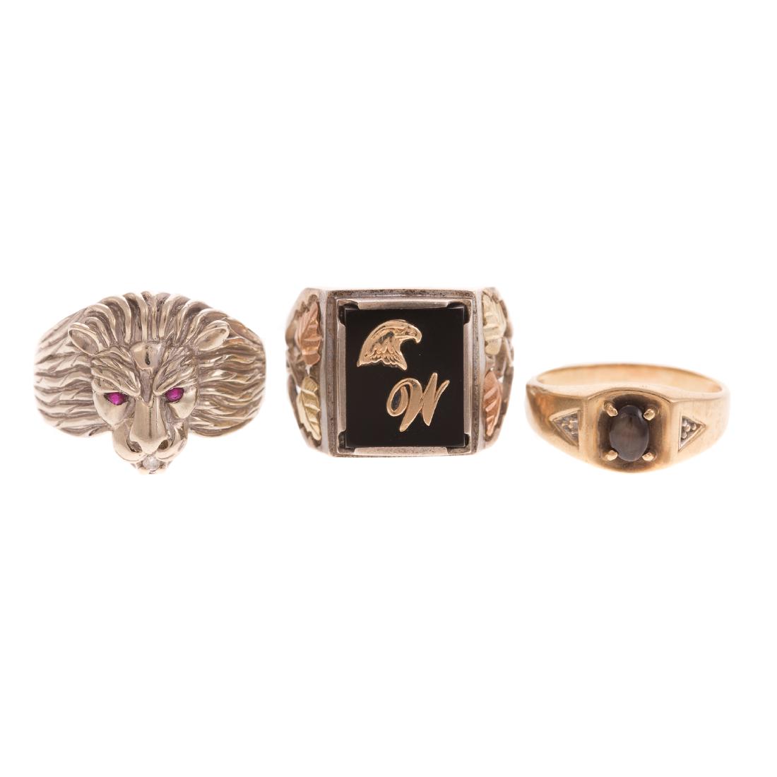 A Trio of Gent's Rings in Gold & Silver: 1) 10K yellow gold ring featuring black star sapphire in the center, sz 8.5, 2) 10K white gold lion ring with ruby eyes, sz 10 and 3) Sterling silver ring with 10K tri gold accents, sz 11.5, 16.8 gram