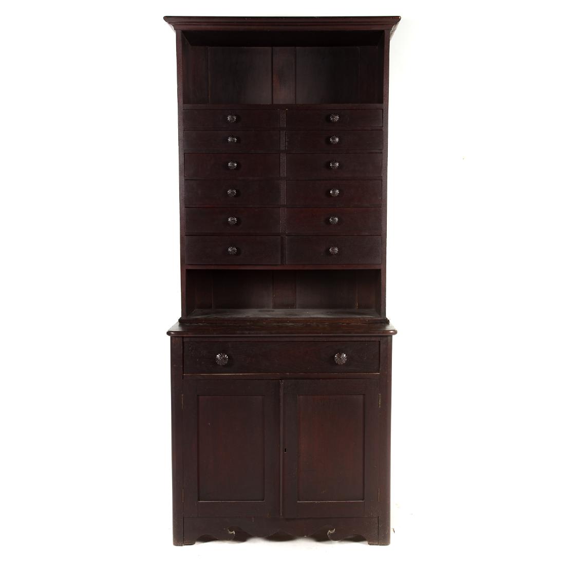American Walnut Apothecary Cabinet: mid-19th century; flat top with molded cornice, open shelf and twelve graduated drawers in upper case; long drawer and compartment enclosed by flat paneled doors in lower case, shaped apron, 81 1/2 in