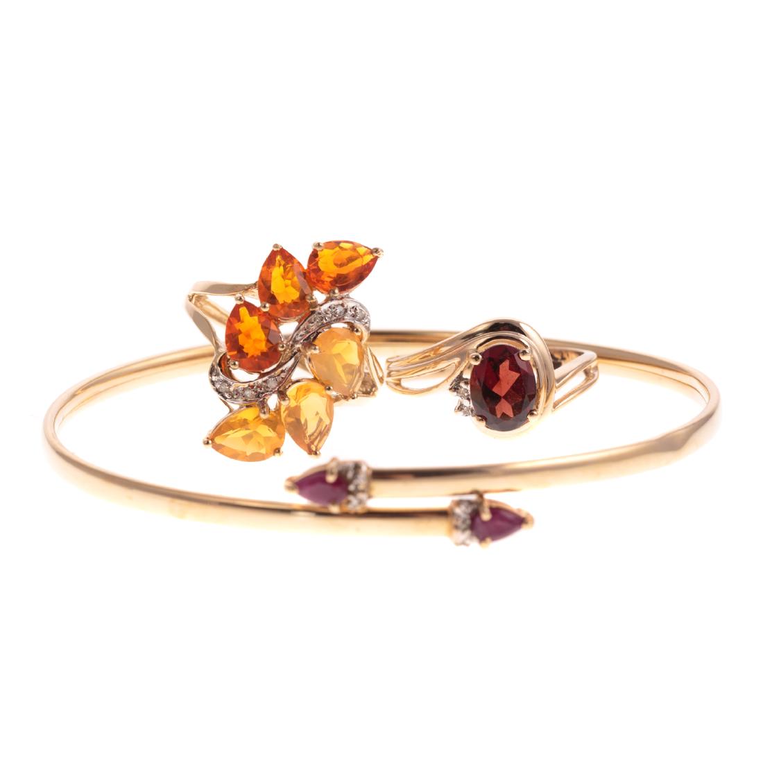 A Ruby & Diamond Bracelet & Two Gemstone Rings: 1) 14K yellow gold bracelet featuring a pair of pear shaped rubies, accented by diamonds, 2.5 in. D, 2) 14K yellow gold oval garnet ring adorned by two diamonds, sz 7.25, and 3) 10K yellow gold cluste