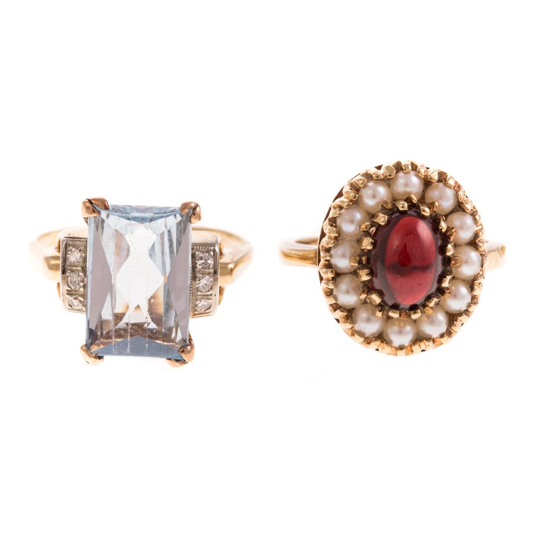 A Pair of Ladies Gemstone Rings in 14K Gold: 1) 14K yellow gold ring featuring an oval garnet cabochon surround by seed pearls, in a classic setting, sz 5, and 2) 14K yellow gold ring comprised of an aquamarine stone, decorated by six diamonds, 