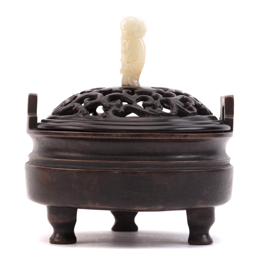 Chinese Bronze Censer: cast bronze three foot circular censer, with carved reticulated wood lid with carved figural knop, possibly jade, having character mark underneath, 7 in. H., 6 in. Diam., with wood storage box having