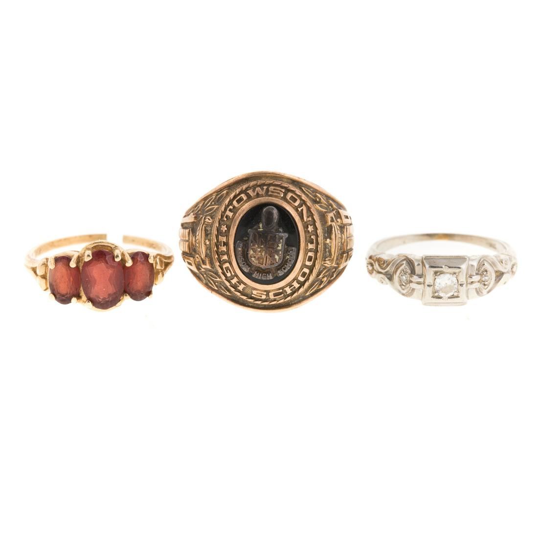 A Trio of Ladies Gemstone & Diamond Rings in Gold: 1) 18K white gold diamond engagement ring with diamonds, approx. 0.20ctw, sz 5, 2) 14K yellow gold ring featuring 3 oval garnets, sz 6, shank is split and 3) 10K yellow gold 1959 Towson High School cl