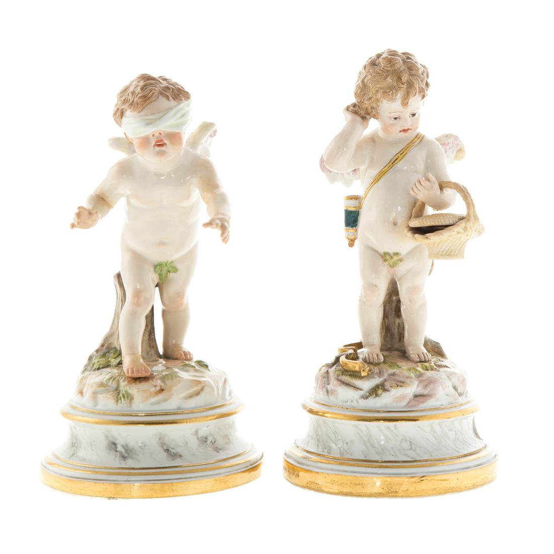 Two Meissen Porcelain Cupids: late 19th century; underglaze blue crossed swords mark, incised "L118" and "L119" marks. One carrying a basket, 7 1/2 in. H.; one wearing a blindfold, 7 in. H.Estate of Leo and Martha Leckar. Acquired
