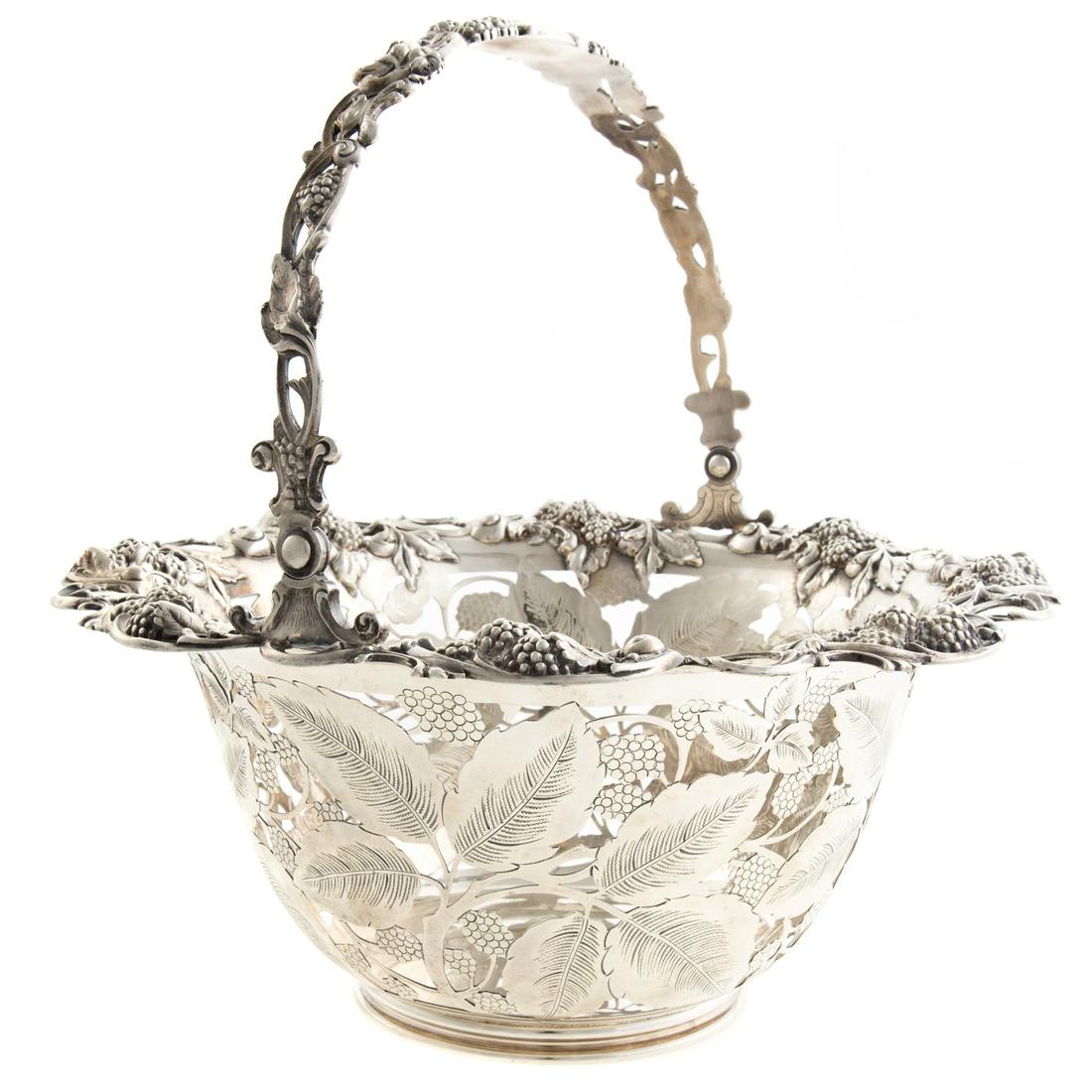 A Tiffany & Co Sterling Silver Center Basket: 1902-1907 date mark, pattern #16201, gently flaring circular form, the body of open work leafy raspberry decoration, rim with applied scrolls and raspberries, similar swing bail handle, engraved with