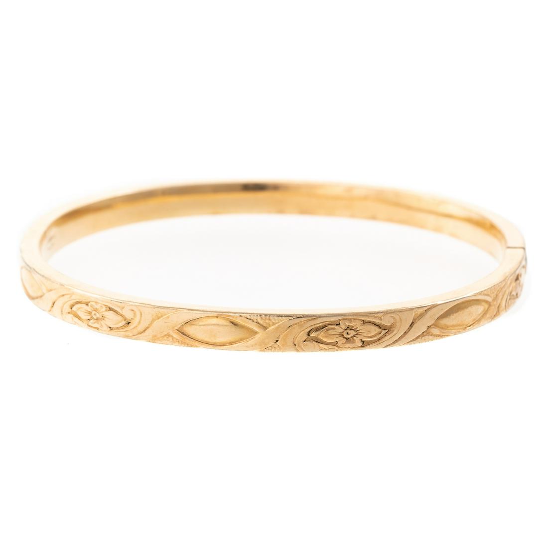 A Carved Flower & Swirl Bangle in 18K: 18K yellow gold bangle with carved flower and swirl design, 2.5 in. D, 9.4 grams. The estate of Gloria Corn, Washington, DC