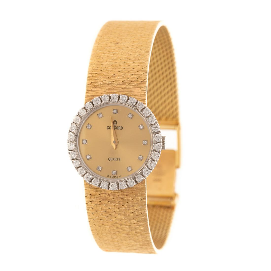 A Lady's 14K Gold Concord Diamond Wrist Watch: 14K yellow gold lady's Concord wrist watch, c. 1980, brushed gold dial with diamond hour indicators, dial reads "Concord quartz," accented by a diamond bezel, on a textured mesh bracelet, case stamped