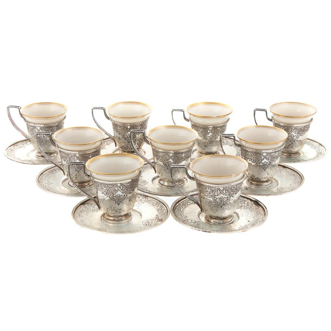 Nine Sterling Demitasse Cups & Undertrays: retailed S&N Katz, Baltimore; each with hammered body, and chased stylized foliate border, the cups with monogram and Lenox porcelain liner, cups are 2 1/4 in. H., overall, undertrays are 3 1/2 in. Di