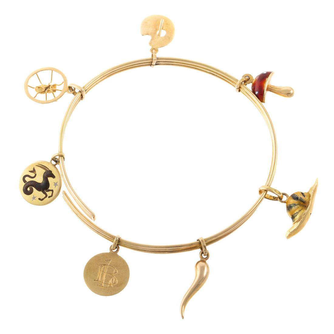 A Bangle Charm Bracelet in 18K & Seven Gold Charms: 18K yellow gold ridged bangle features various charms, including artist's palette with enamel paint, enamel Capricorn symbol, gold tamale, snail with enamel shell, red enamel mushroom, gold spider, an