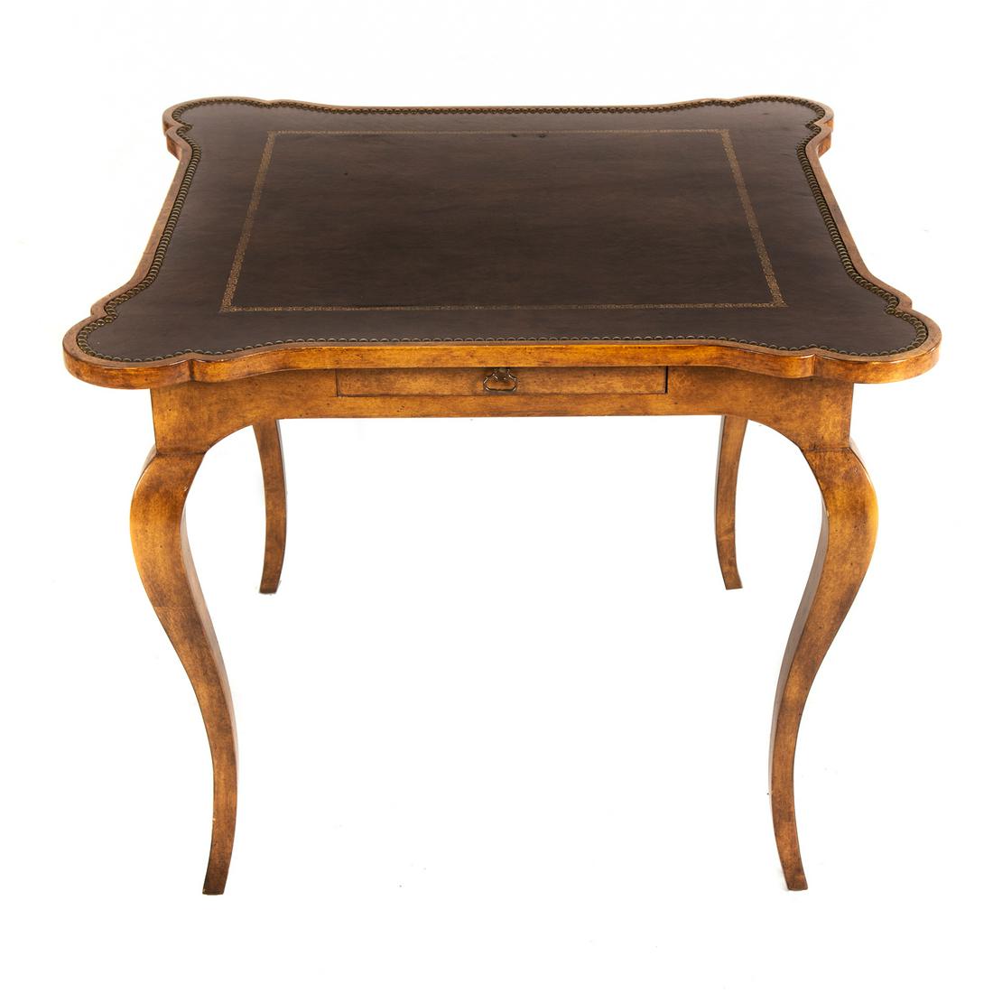 Minton Spidell Leather Top Games Table: Shaped top with turret corners, leather top surface, with gold leaf boarder and nail head trim, with one drawer, on cabriole legs. 29 in. H., 36 in. L., 36 in. D.