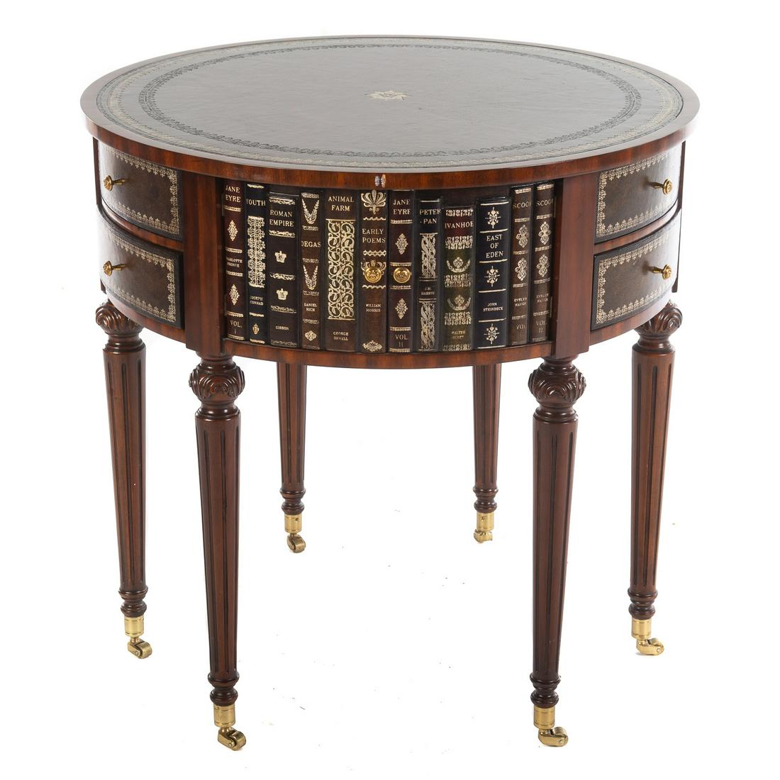 Maitland Smith Leather Top Drum Table: With painted leather edge to simulate books, with two pairs of cabinet doors and two pairs of stacking drawers, with carved reeded legs ending in brass castors. 30 in. H., 30 in. Diam. From the Privat