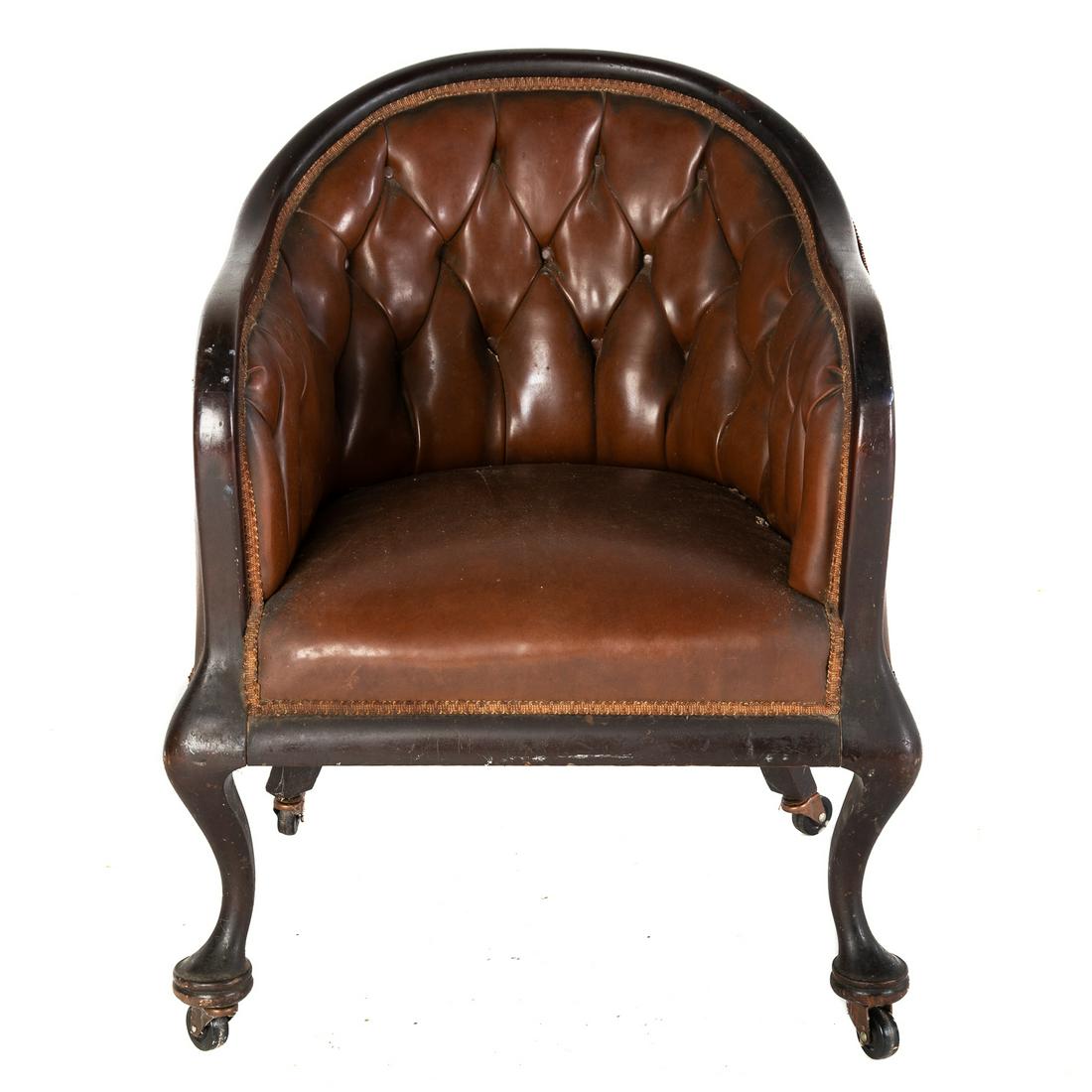 Edwardian Bank of England Chair: Early 20th century; carved wood frame with leather button back upholstery, on cabriole legs with large castors. 34 in. H., 25 in. W., 28 in. D.