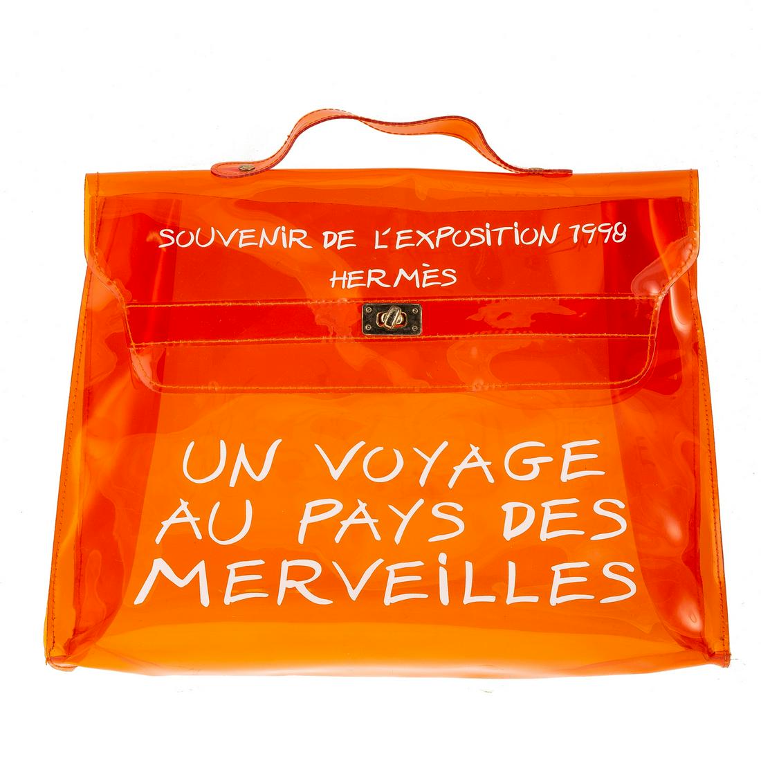 A Hermes Souvenir De L'Exposition Kelly: An orange vinyl Hermes Kelly Souvenir handle bag with gold plated hardware, single flat top handle, white 'Souvenir de L'Exposition' motif at face. Tonal vinyl lining and turn-lock closure at front fl