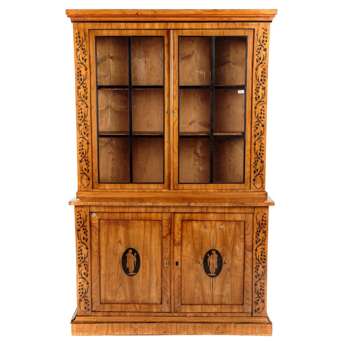 Biedermeier Inlaid Satin Wood China Cupboard: Circa 1870; two-part china cupboard, top case with ebonized vine inlay and mullions, interior with fixed shelves, bottom case with pair of panel doors, ebonized vine inlay, each door with inlaid class