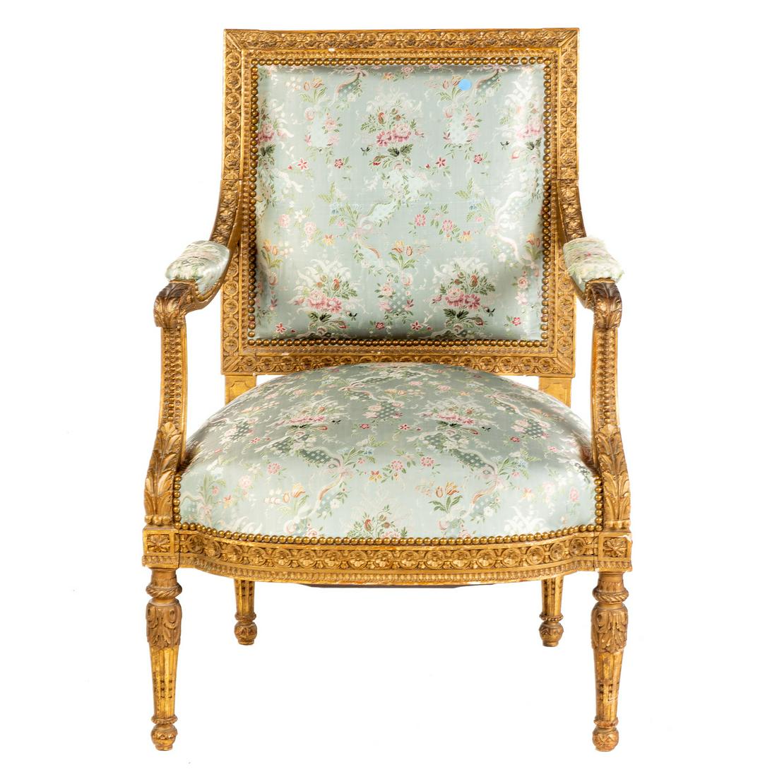 Louis XVI Style Giltwood Arm Chair: 19th century; elaborate floral rosettes and foliate carving, covered in gilt with floral silk upholstery. 39 in. H., 26 in. W., 23 in. D.
