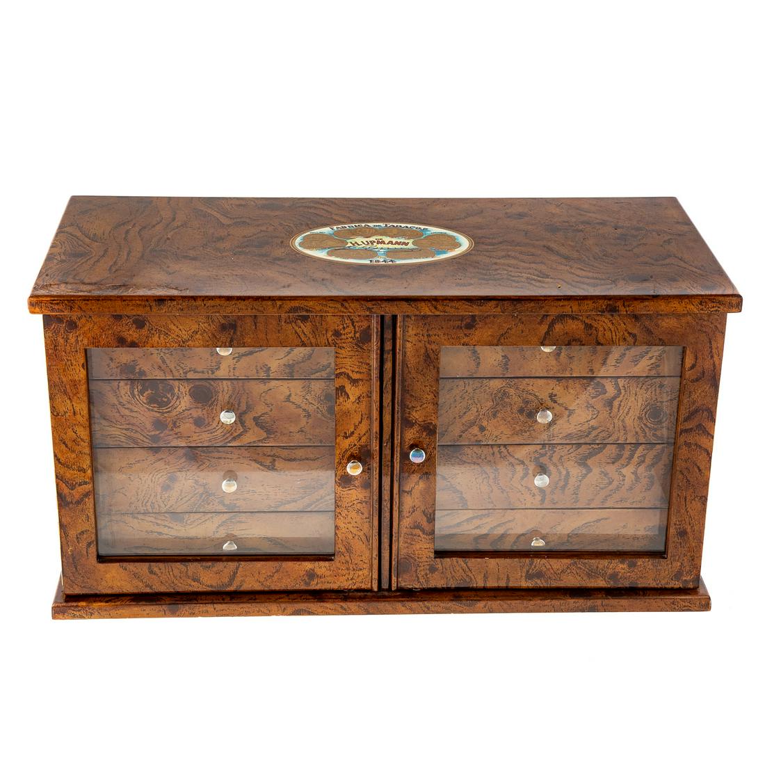H. Upmann Burled Wood Cigar Humidor: Lacquered burl wood case, decorated with Upmann cigar box label on top, with pair of glass panel doors, housing 8 storage drawers with lacquered wood fronts and cedar lining, 12 in. H., 23 in. W., 11 