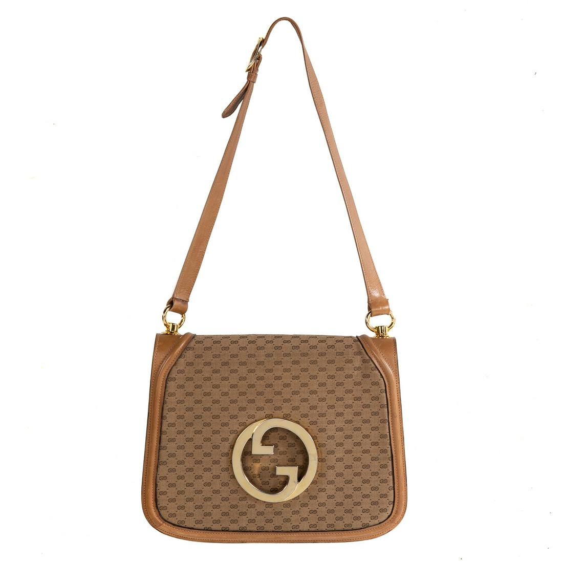 A Vintage Gucci Logo Shoulder Bag: A brown and tan Monogram canvas Gucci Vintage Logo Shoulder Bag with gold tone hardware, leather accents and trim and single adjustable flat shoulder strap. Tonal leather lining with two interior comp