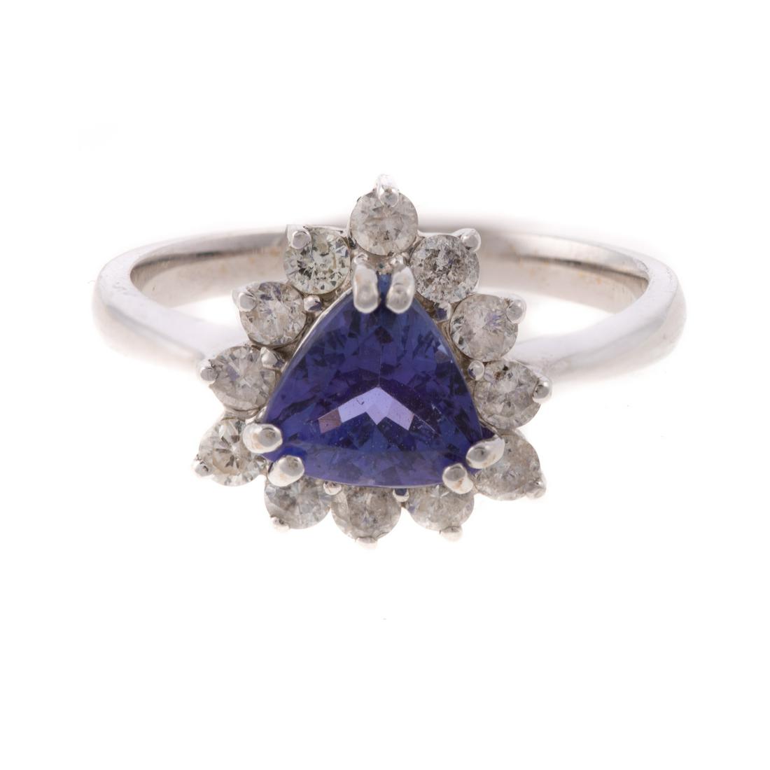 A Tanzanite & Diamond Ring in 18K: 18K white gold ring featuring a trillion cut tanzanite, weighing approx. 1.20 cts, set in a double prong mounting and surrounded by a halo of round cut diamonds, sz. 7.25, 4.0 grams