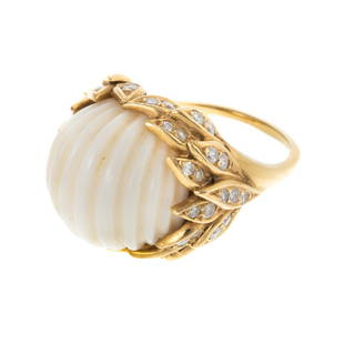 A 1970s Van Cleef & Arpels Carved White Coral Ring: c. 1970, 18K yellow ring by Van Cleef & Arpels with gold foliage mounting featuring a carved round white coral, measuring approx. 16 mm D., surrounded by leaves set with fifty bead set round-cut