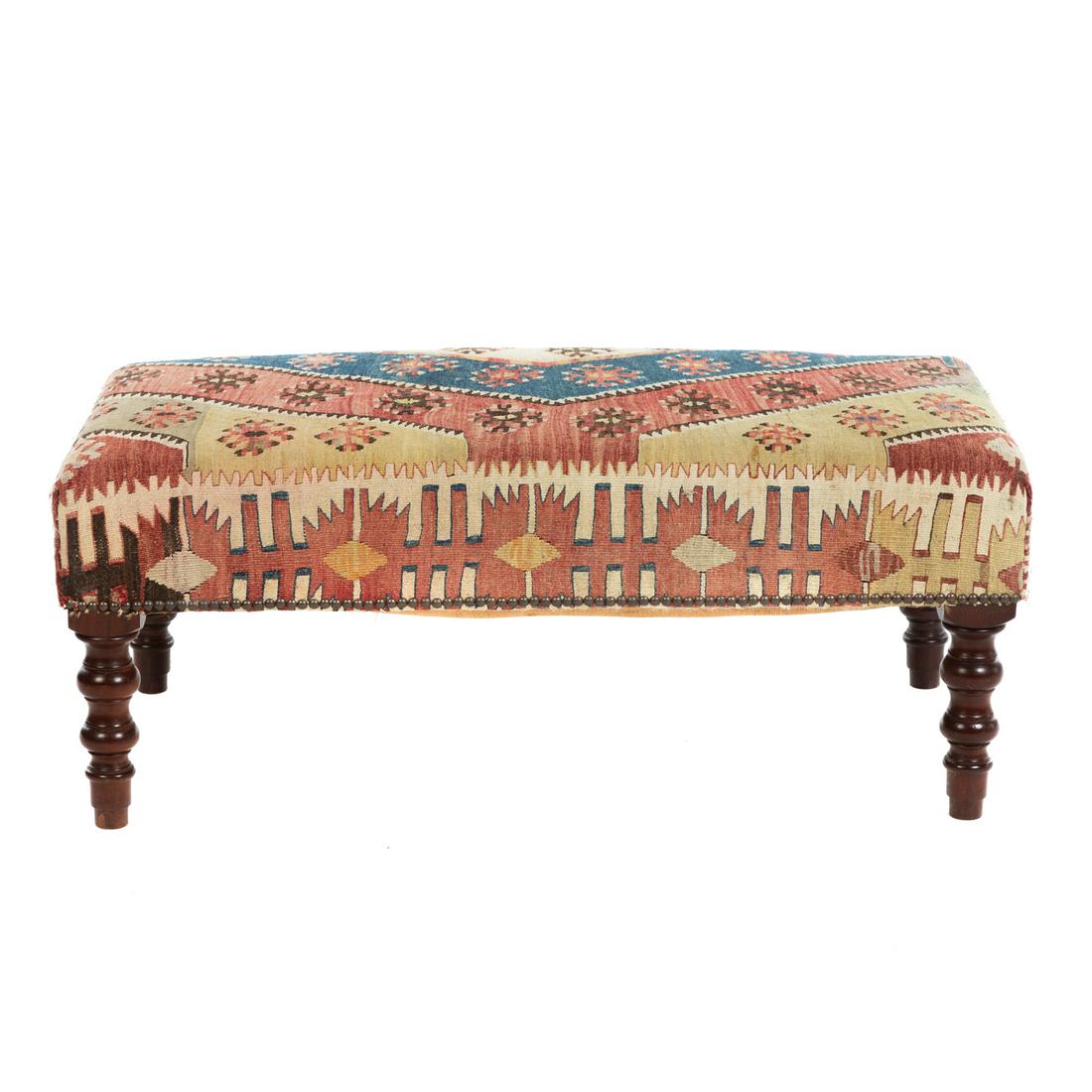 Victorian Kilim Upholstered Bench: Late 19th century; with Kilim upholstery with brass tacks on turned legs, 16 in. H., 37 in. W., 19 in. D. Estate of Valerie Sabet, socialite, antique dealer and collector, New York, NY.