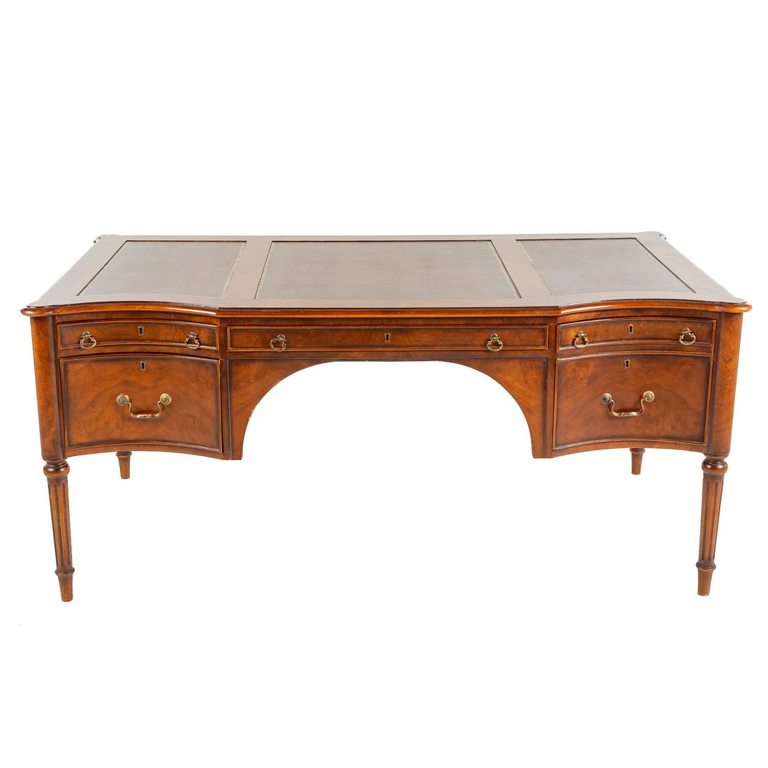 Walnut Leather Top Executive Desk: 20th century; shaped top with inset leather writing surface, having single long drawer flanked by two stacking drawers on one side and a double file drawer on the other, on reeded legs, 30 in. H., 67