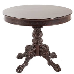 American Classical Carved Mahogany Center Table: Circa 1830; molded edge with elaborate foliate carved pedestal, legs, and paw feet, 29 in. H., 36 in. Diam.