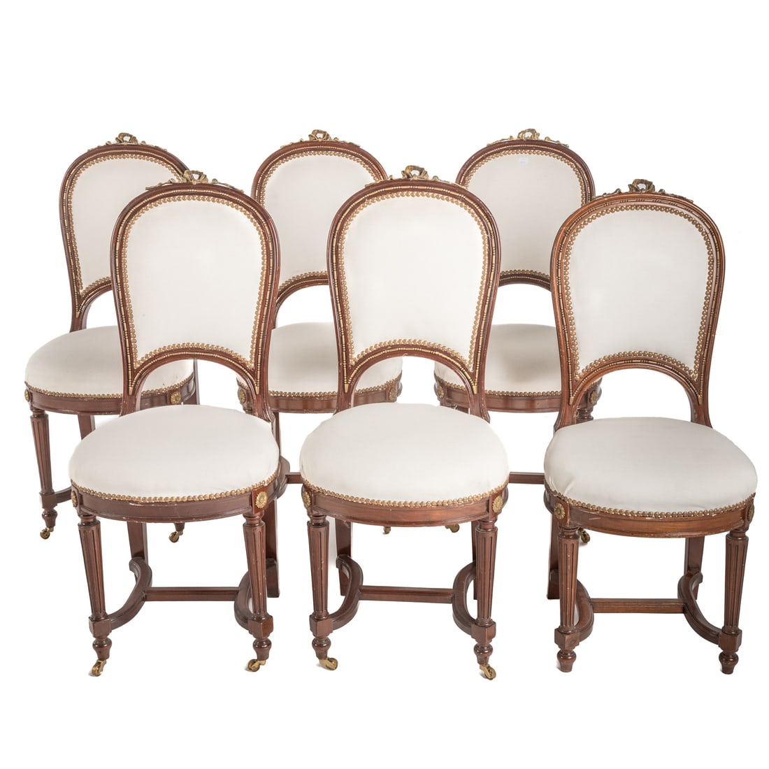 Six Louis XVI Style Upholstered Chairs: 20th century; brass mounted mahogany frames with tack head upholstery, reeded legs with stretcher bases and casters, upholstered seat and back, 38 in. H., 16 in. W., 15 in. D.