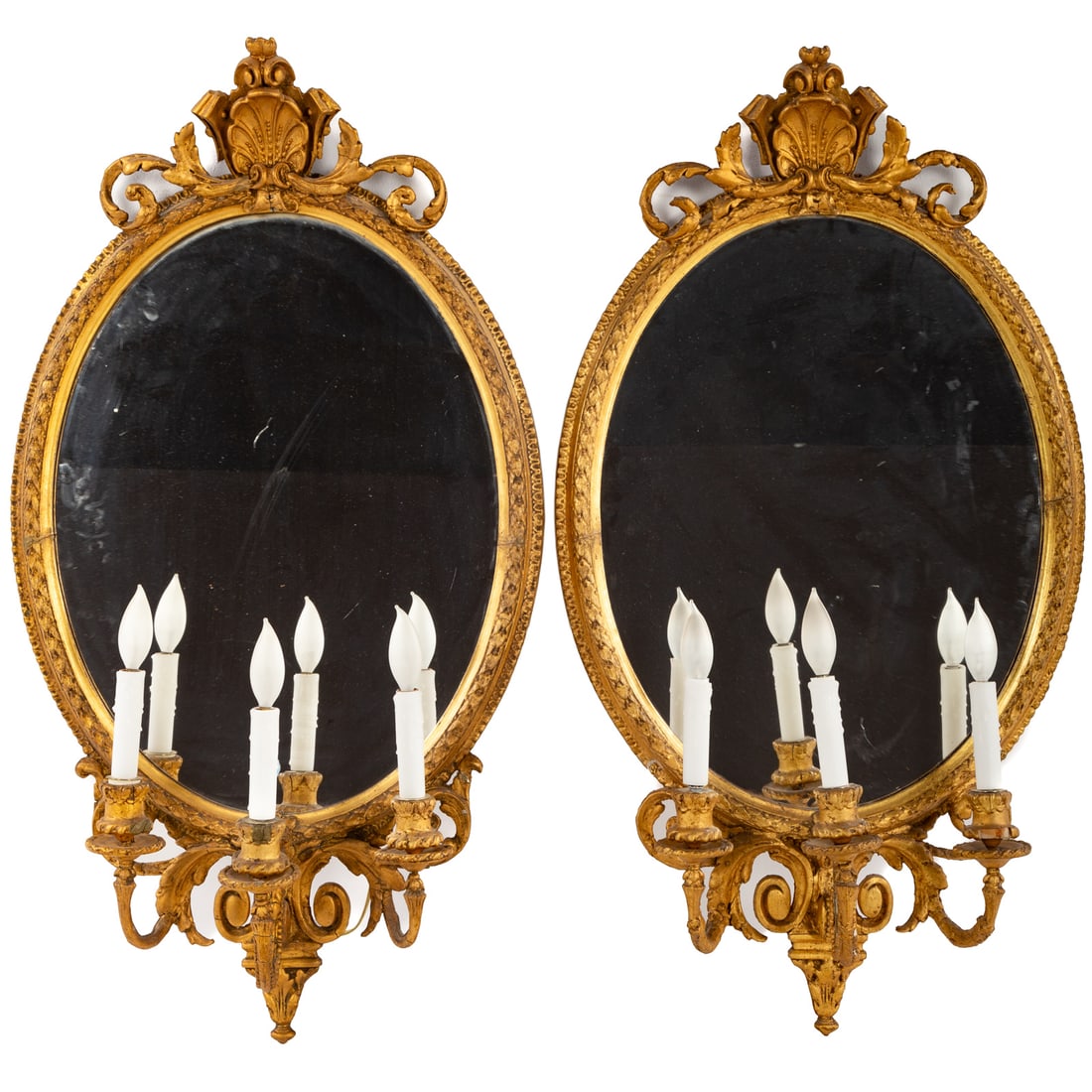 A Pair of Georgian Style Gilt Three Light Sconces: 20th century; oval shell topped carved gilt wood three light mirrored sconce, 39 in. H., 21 in. W.