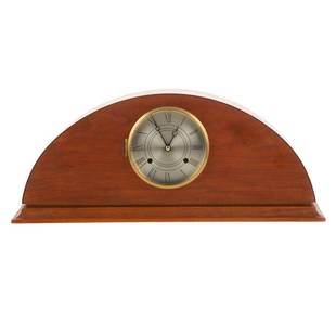 Thomas Moser Cherry Mantel Clock: 21st century; demilune veneered case with molded base and silvered metal face, marked on verso,"Thos. Moser Cabinetmakers Chelsea Clock Company," 7 in. H., 17 in. W., with key.