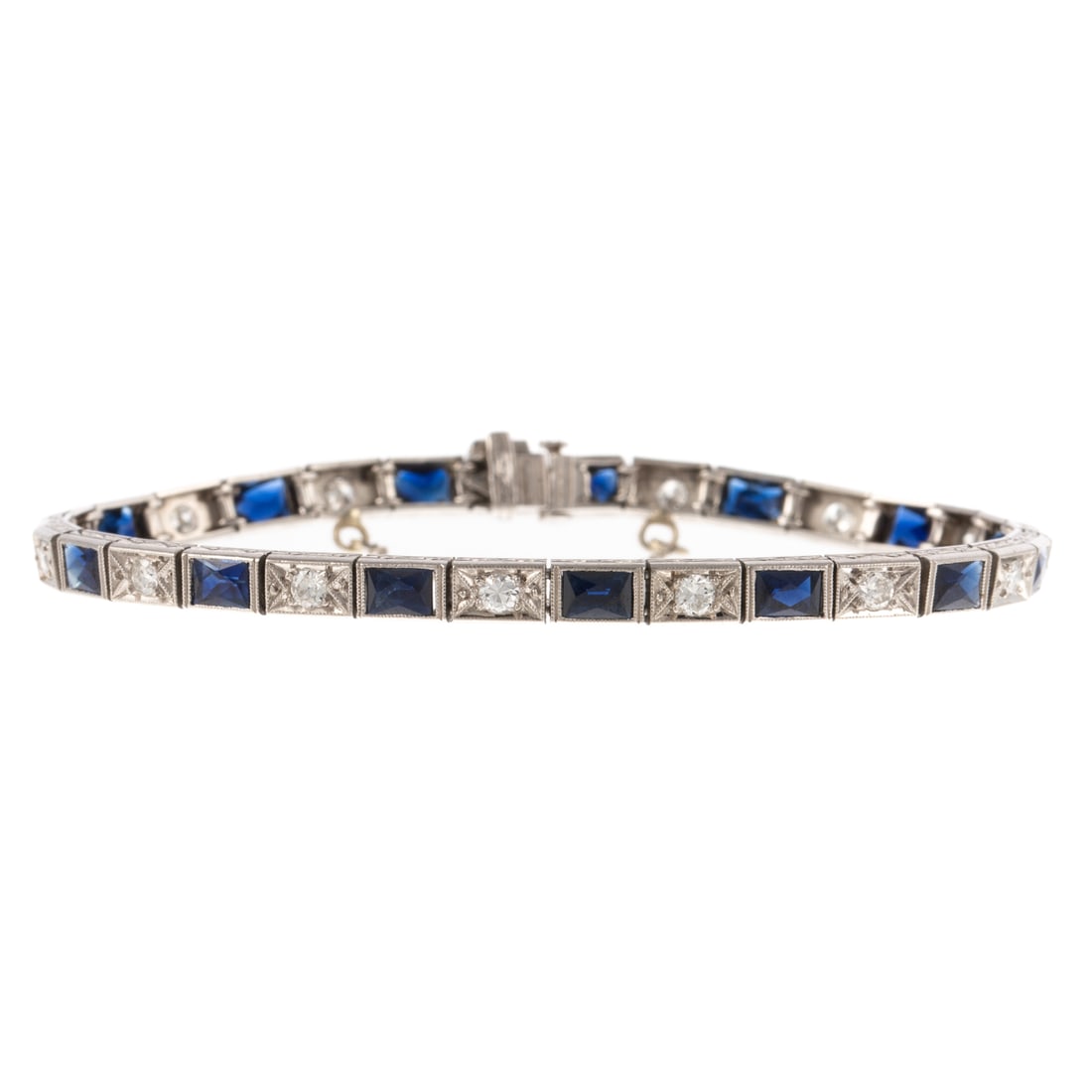 An Art Deco Diamond & Sapphire Bracelet in Platinum: c.1930s platinum line bracelet featuring alternating rectangular links of round diamonds in milgrain work weighing approx. 1.00 ctw and French cut sapphires weighing approx. 7.00 ctw, gallery engraved