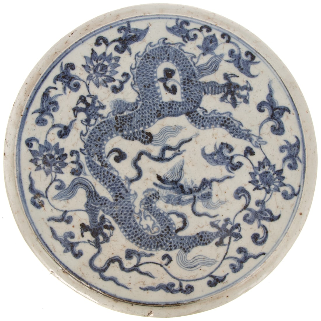 A Chinese Blue & White Porcelain Ming Style Trivet: 19th century or earlier, a Chinese blue and white porcelain Ming style round trivet with unevenly darkened crackling, depicting a five-toed dragon with floral motifs, 3 /4 in. H, 12 in. Diam.