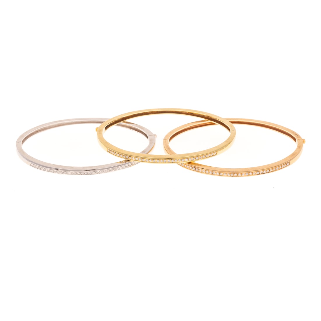 A Trio of Diamond Bangles in 18K: 18K yellow, rose and white gold Italian oval hinged bangles, each featuring a row of round diamonds weighing approx. 0.30 ctw, bead set along one half, the other half high polish, hinged and with hidd