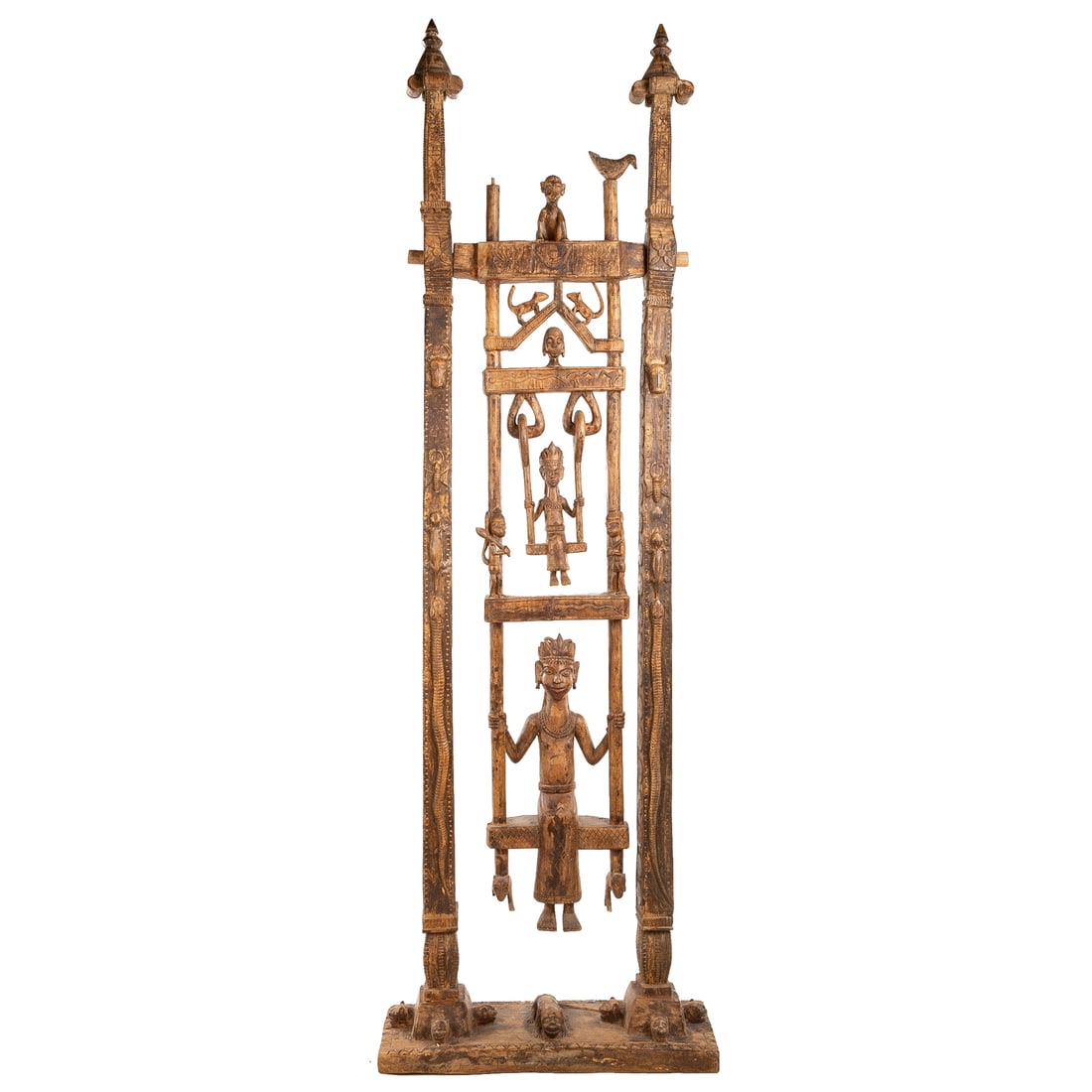 An Indian Articulated Wood Sculpture: Fourth quarter, 20th century, possibly Bastar peoples, presenting two figures on swings, supported on a tall frame, carved all around with animals and floral forms in relief; carved wood with a lightl